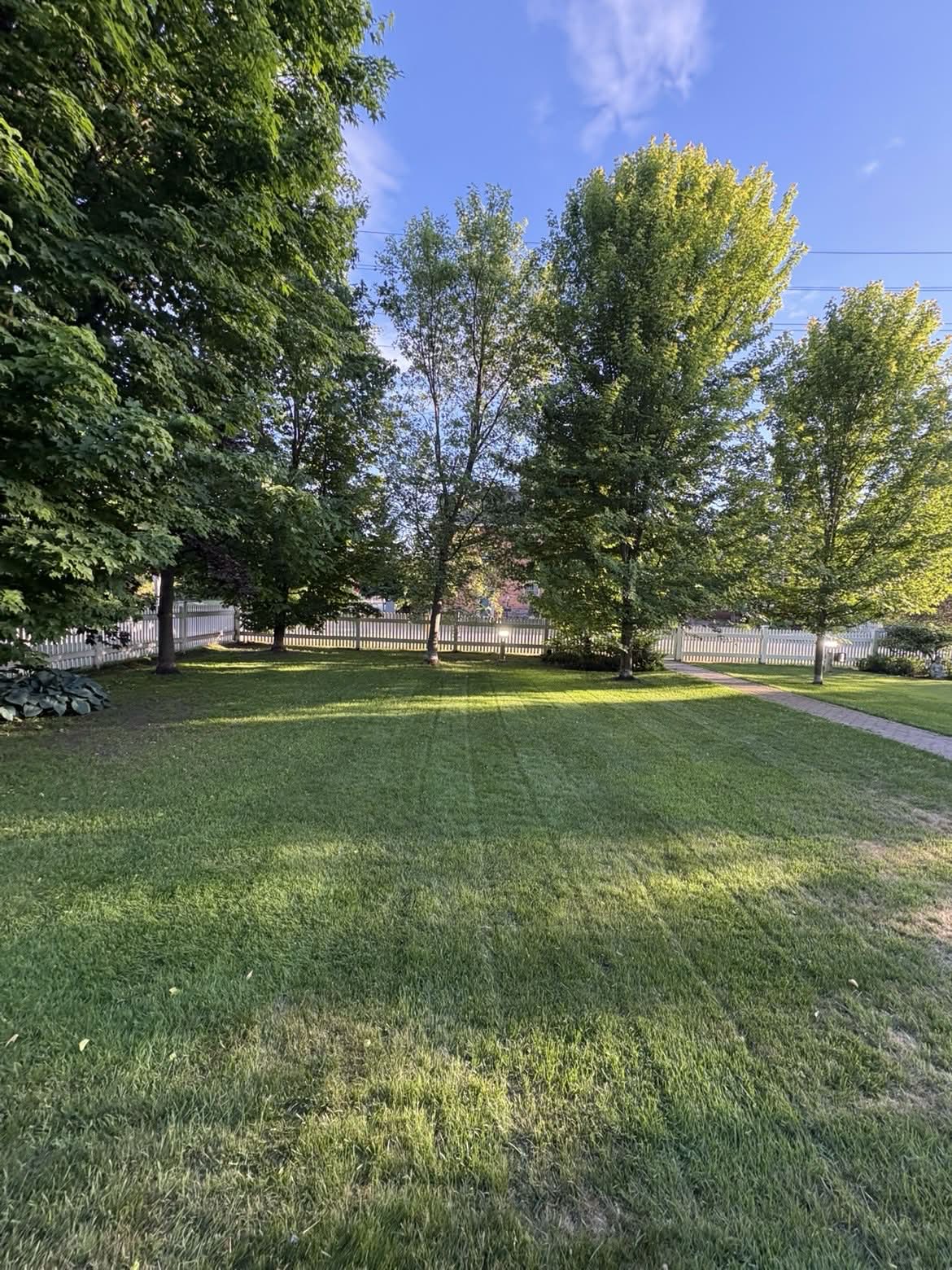 Manicured front lawn beside a white picket fence