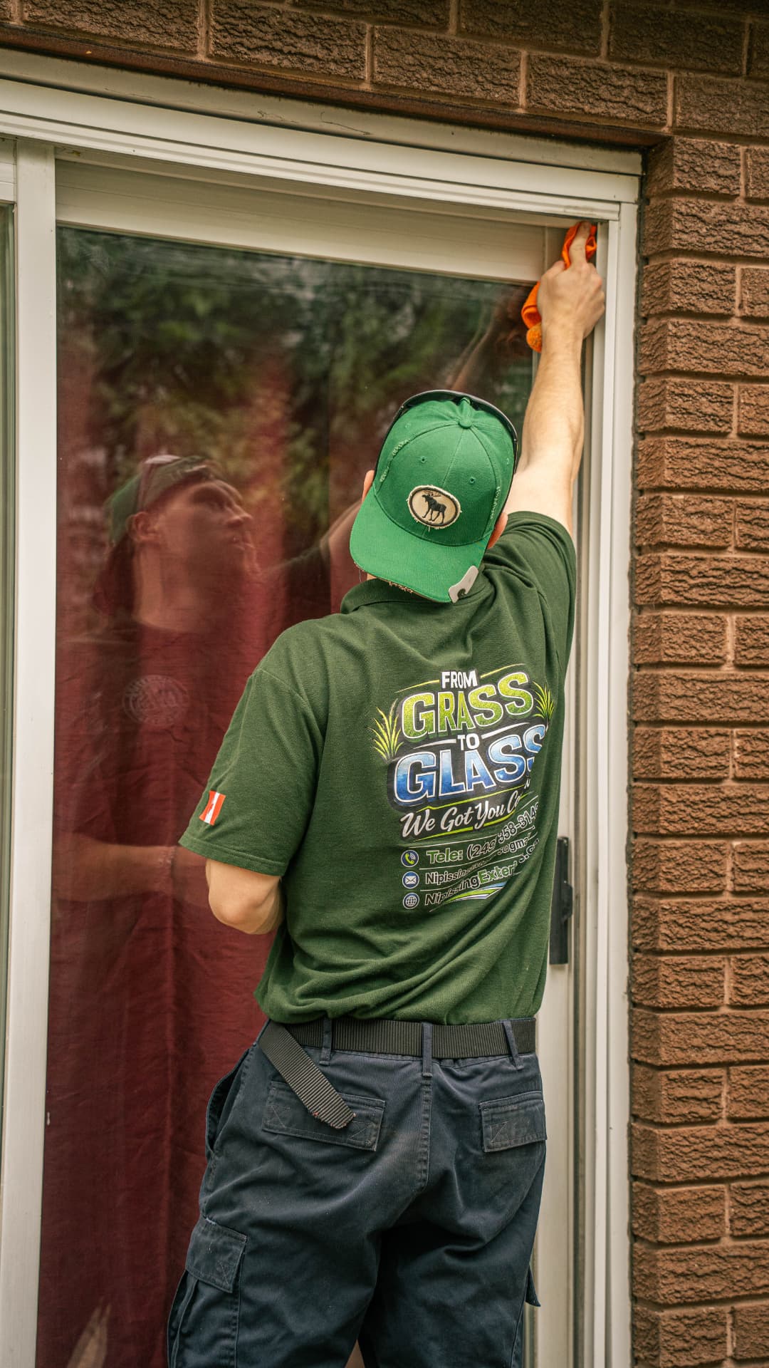Technician wiping a sliding glass door frame during a window cleaning visit